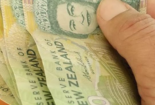 Very close up shot of five New Zealand $20 notes. The are being held by a man, with only his thumb in the shot