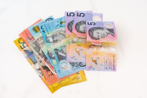 Australian paper currency, spread/fanned out flat on a white surface. There are $50, $20, $10 and $5 notes.