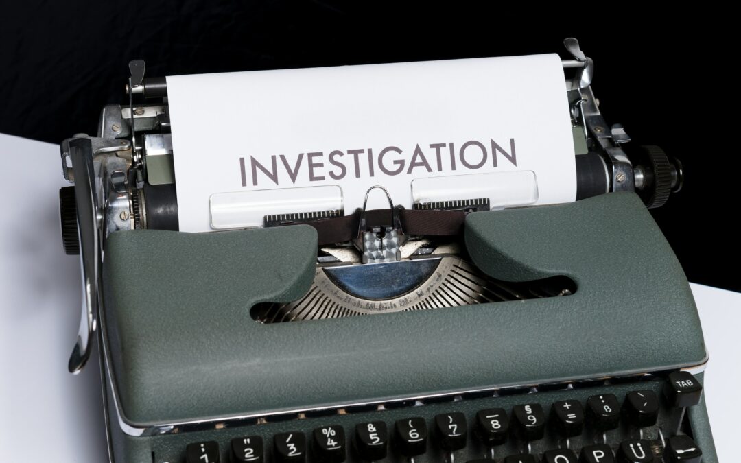 Old fashioned typewriter sitting on desk. White paper in the typewriter has the heading "Investigation" written at the top