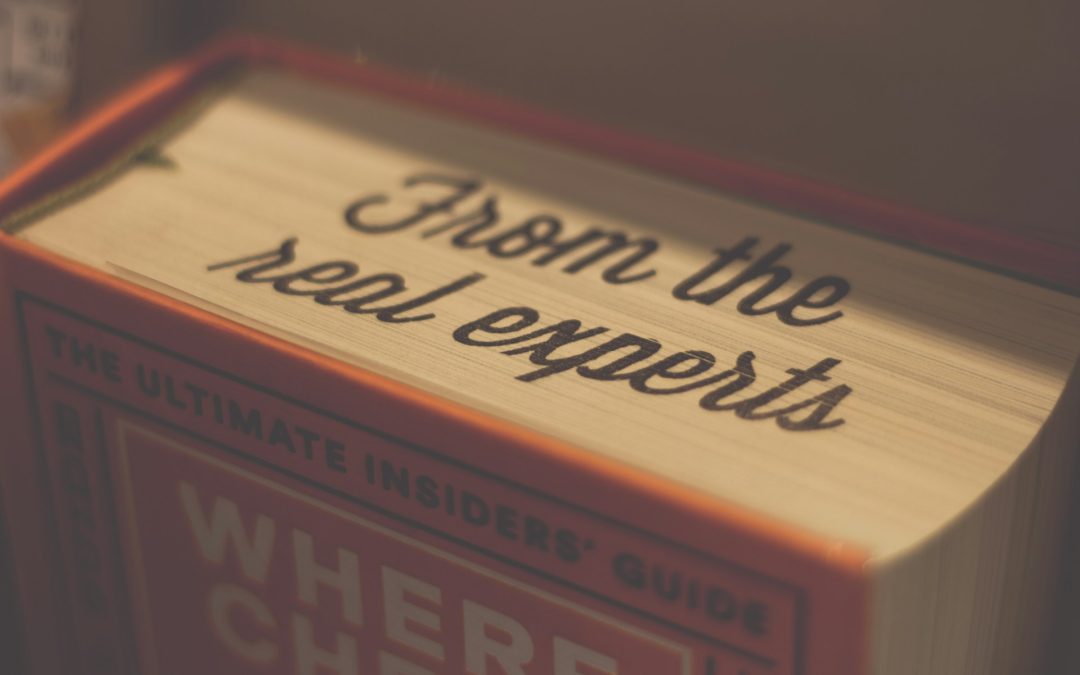 Close up view of an orange book, standing on it's end, being looked at from above. The words "From the real experts" are written across the top edges of the pages.