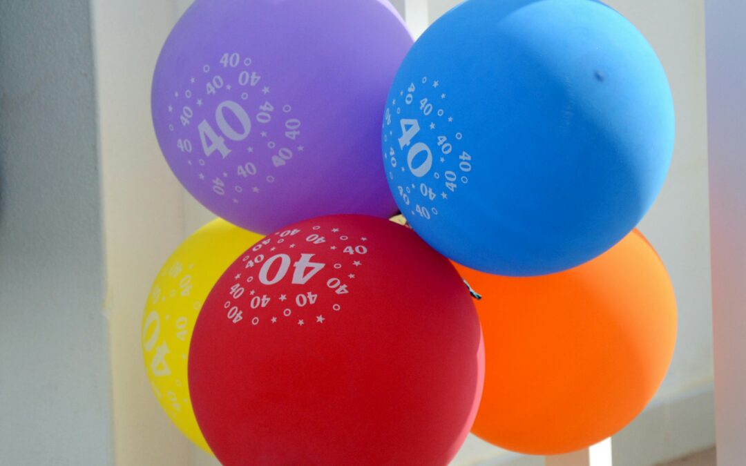 A bunch of five balloons - purple, blue, yellow, red and orange. all have the number 40 on them.